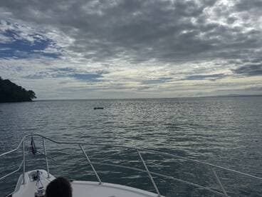 A serene view of the ocean with dramatic clouds, captured from the bow of a boat, showcasing the tranquil beauty of a day on the water.