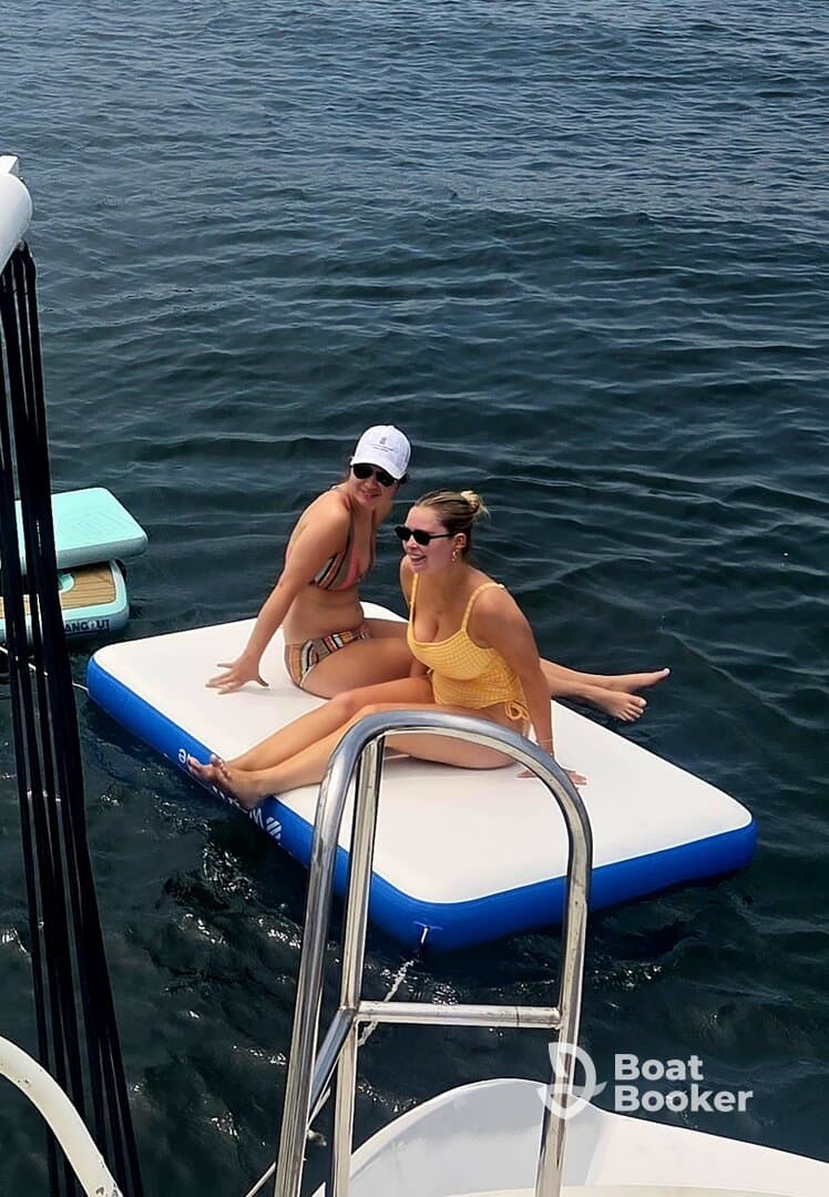 Two friends enjoy a sunny day on a floating mat in the water, capturing the essence of summer fun and relaxation on the water.