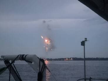 A stunning display of fireworks lights up the night sky, viewed from a boat — a perfect backdrop for celebrations on the water.