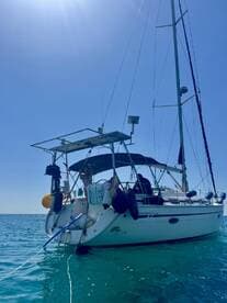 A beautiful sailing boat anchored in clear waters, with guests enjoying the sun and sea — perfect for a day of relaxation and adventure on the water.