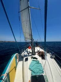 A relaxing day on the water as guests enjoy sunbathing on the deck of a sailboat, surrounded by the beautiful ocean scenery.