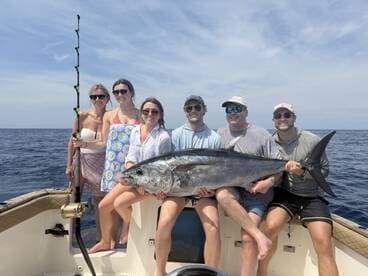 A group of friends proudly displays their impressive catch while fishing at sea, capturing the excitement of a successful day on the water.