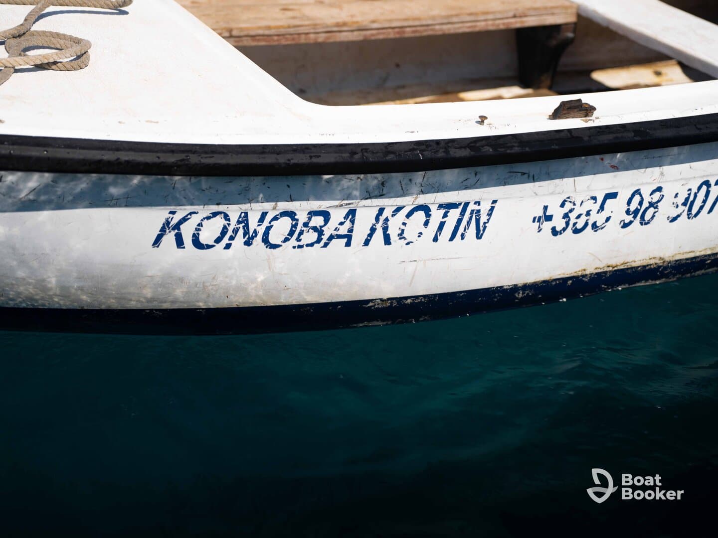 Close-up of a boat's name and contact number, showcasing the vessel's details against a serene turquoise backdrop.