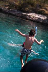A child joyfully jumps into the clear waters, ready for a snorkeling adventure — a perfect moment of fun and excitement on a family boating trip.