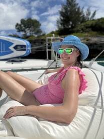 A woman enjoys a sunny day lounging on a catamaran, showcasing the perfect blend of relaxation and fun on the water.