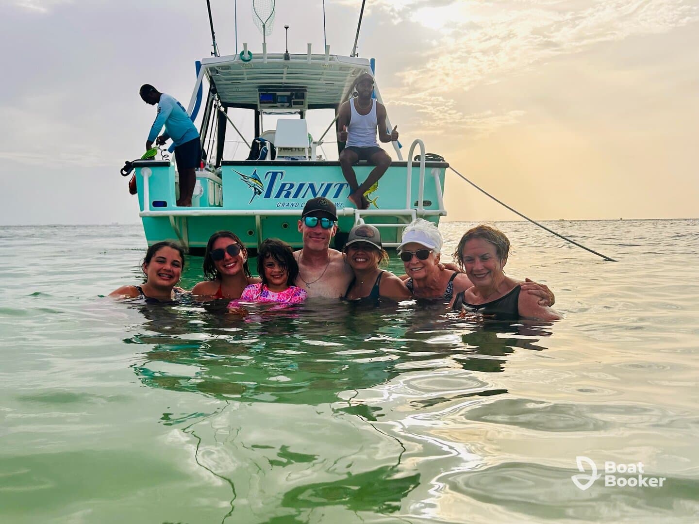 A joyful group of family members enjoys a refreshing swim in the ocean, with their boat anchored nearby, creating unforgettable memories during a sunset cruise.