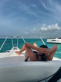 A young woman relaxes on the deck of a boat, enjoying the sun and turquoise waters — a perfect moment for leisure on the water.