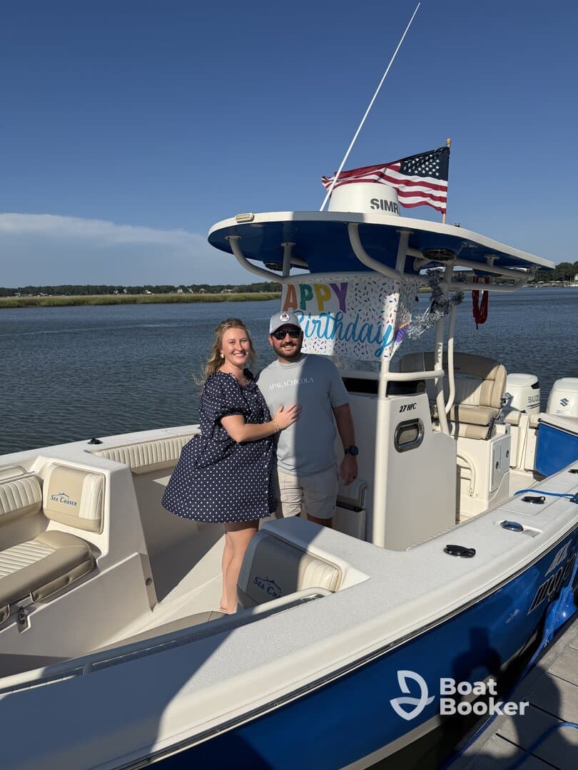 A couple celebrates a birthday on their boat, showcasing a festive atmosphere with decorations and a beautiful waterfront backdrop.