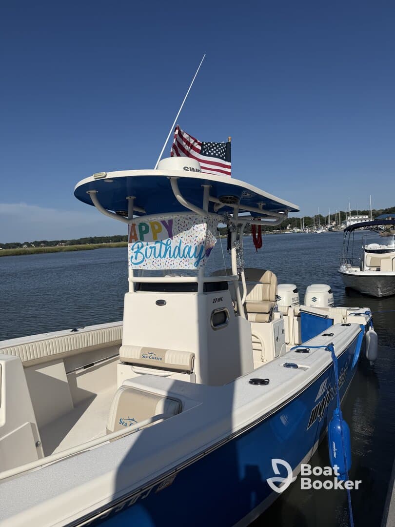 A vibrant view of a Sea Chaser boat adorned with a 'Happy Birthday' banner, docked in calm waters — perfect for celebrating special occasions on the water.