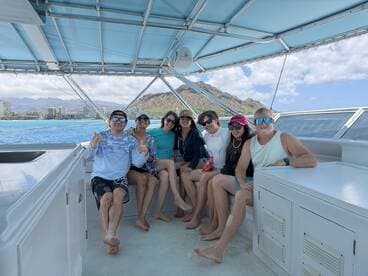 A cheerful group of friends enjoys their time aboard a boat, surrounded by stunning ocean views and mountains — perfect for memorable adventures on the water.