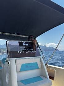 A view of the helm area inside a boat, featuring a captain at the wheel and a comfortable seating area, perfect for enjoying a day on the water.