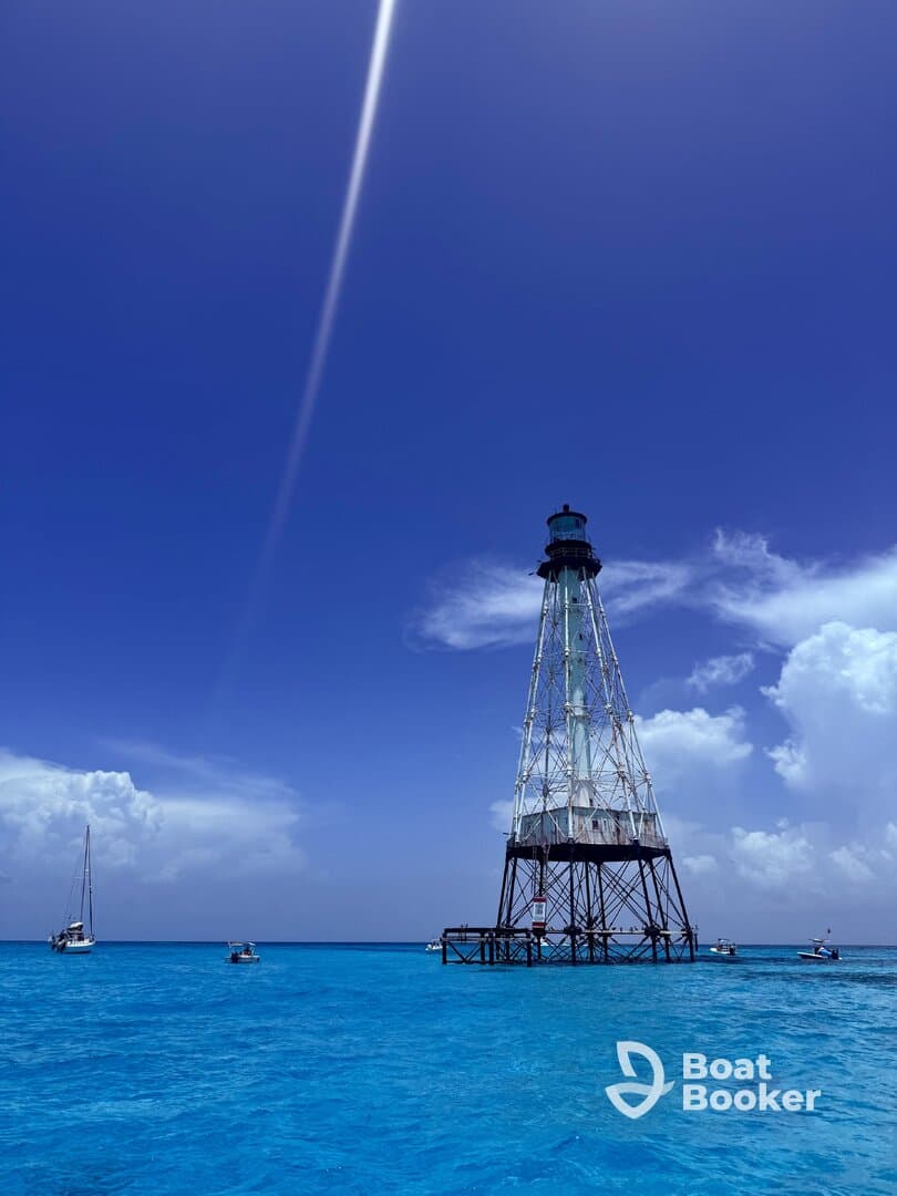A stunning view of a lighthouse standing tall over vibrant turquoise waters, surrounded by boats — a picturesque scene perfect for island adventures.