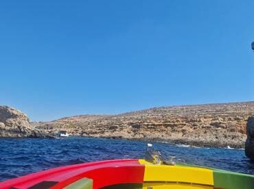 A vibrant view from the bow of a boat cruising along a stunning coastline, showcasing the natural beauty of the rocky landscape and clear blue waters.