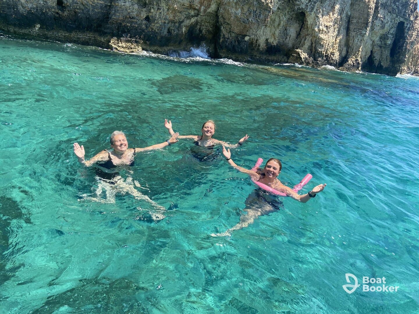 Three friends enjoy a refreshing swim in crystal-clear waters, celebrating a perfect day on the water — ideal for summer adventures and group outings.