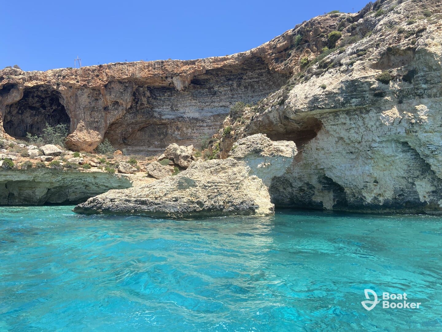 A stunning view of rocky cliffs and crystal-clear turquoise waters, showcasing the natural beauty of the coastline — perfect for scenic boat tours and exploration.