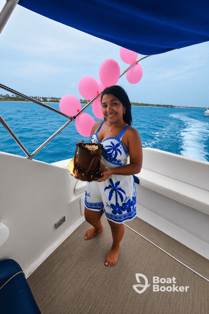 A woman celebrates with a birthday cake on a boat, surrounded by festive pink balloons — perfect for memorable celebrations on the water.