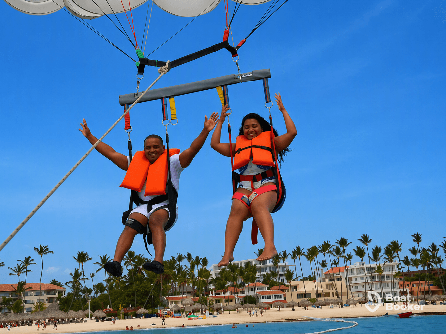 A couple enjoys an exhilarating parasailing experience over a beautiful beach, capturing the thrill of adventure in a tropical paradise.