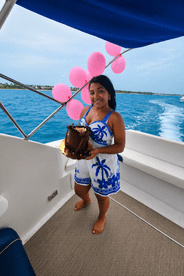 A woman celebrates with a birthday cake on a boat, surrounded by festive pink balloons — perfect for memorable celebrations on the water.