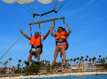 A couple enjoys an exhilarating parasailing experience over a beautiful beach, capturing the thrill of adventure in a tropical paradise.