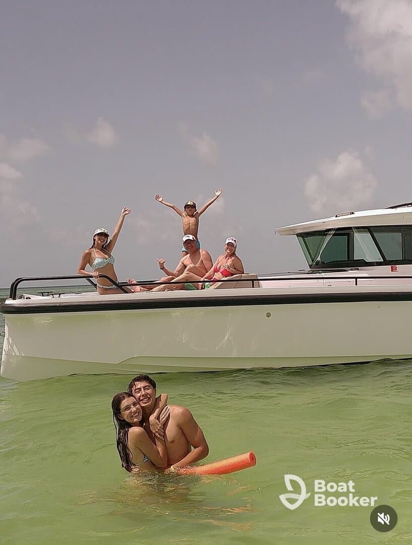 A joyful group enjoys a fun day on the water, celebrating with swimming and laughter around a pontoon boat — perfect for family outings and summer adventures.