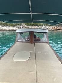 A view from the helm of a boat, showcasing the interior seating and a glimpse of passengers enjoying the ride in tranquil waters.