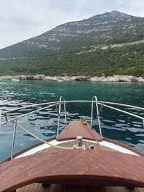 A scenic view from the front of a boat, showcasing the tranquil waters and lush green hills in the background, perfect for exploring coastal landscapes.