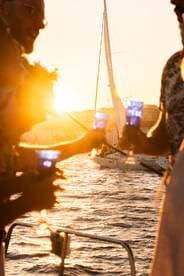 Guests celebrate with cocktails at sunset aboard a sailboat, creating a picturesque moment perfect for memorable sailing experiences.