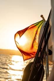 A vibrant Portuguese flag flutters in the breeze against a stunning sunset backdrop, capturing the essence of maritime adventures.