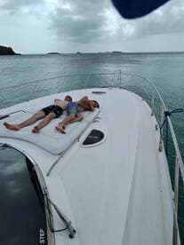 Two friends relax on the deck of a yacht, enjoying the serene waters and a perfect day for sunbathing — an ideal scene for leisure and relaxation on the water.