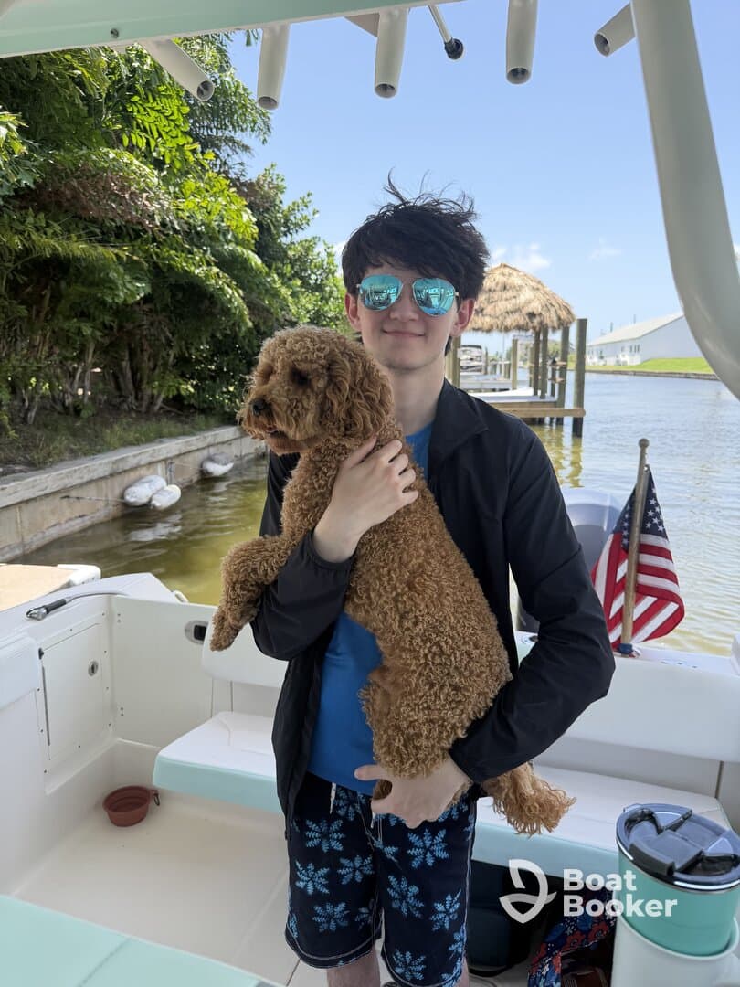 A young boy smiles while holding a dog on a boat, capturing a joyful moment on the water — perfect for family outings and pet-friendly adventures.