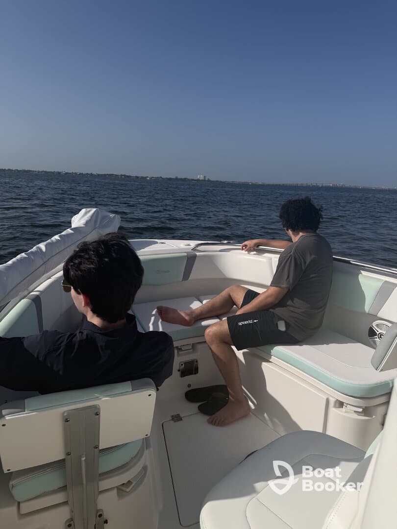 Two guests relax inside a modern boat, enjoying the serene water views. The interior features comfortable seating, perfect for a day out on the water.