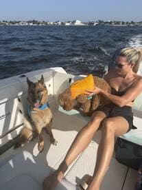 A woman enjoys a sunny day on a boat with her two dogs, showcasing a fun and relaxing boating experience.