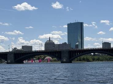 A picturesque view of a city skyline featuring a bridge and colorful sailboats on the water, perfect for showcasing urban boating adventures.