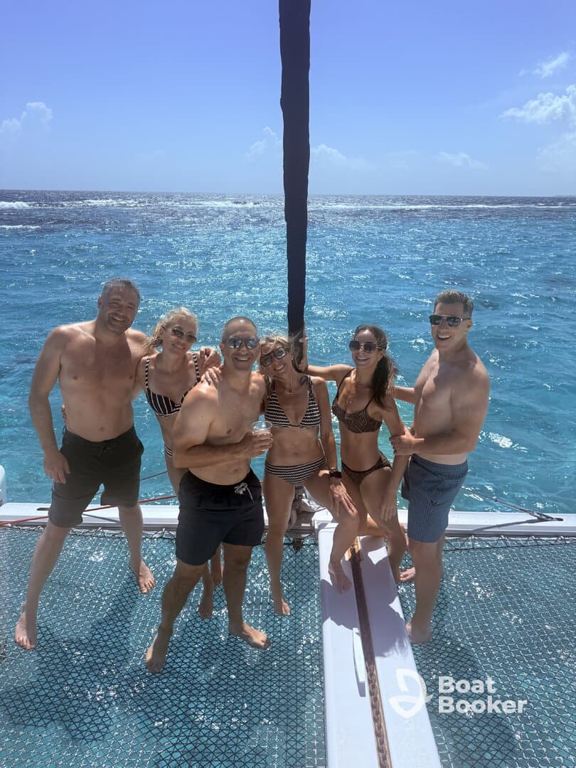 A cheerful group of friends enjoys a sunny day on a catamaran, celebrating and swimming in the vibrant blue waters — perfect for unforgettable summer adventures.
