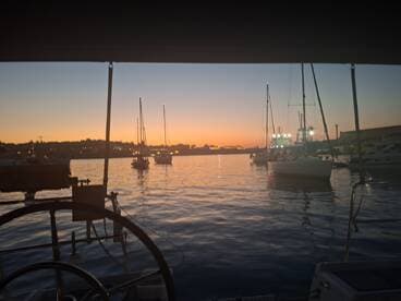 A serene sunset view from aboard a boat, showcasing a harbor filled with yachts and a picturesque skyline — perfect for evening cruises and relaxation on the water.