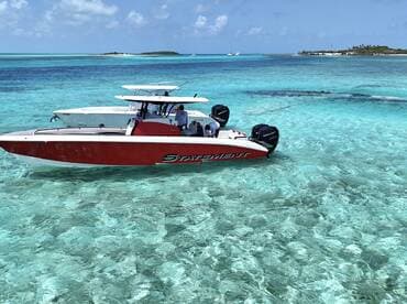 A sleek speedboat navigates through crystal-clear turquoise waters, showcasing the beauty of the surrounding islands — perfect for adventurous outings.