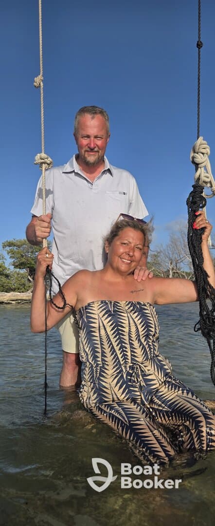 A joyful couple enjoys swinging in shallow water, capturing a fun moment during their boating adventure — perfect for memorable experiences on the water.