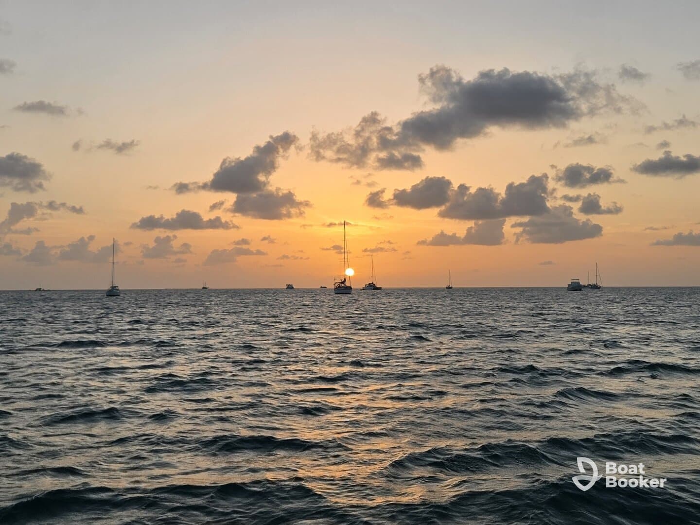 A serene sunset view over the ocean with multiple sailboats silhouetted against the vibrant sky, perfect for capturing the beauty of maritime tranquility.