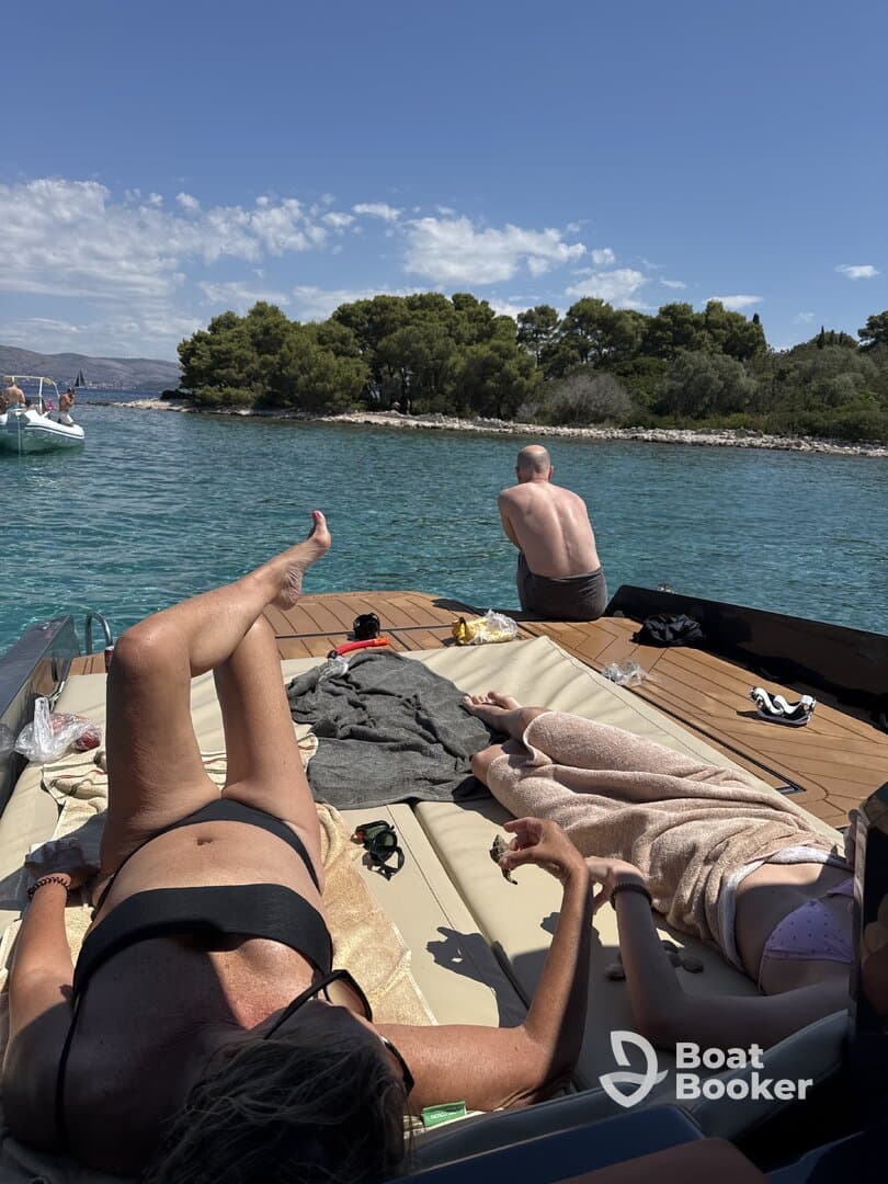A group enjoys a relaxing day on a boat, sunbathing and taking in the beautiful scenery — the perfect summer getaway on the water.