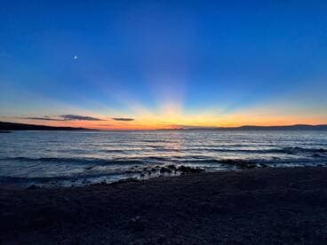 A breathtaking sunset over the tranquil waters, showcasing vibrant colors and a serene coastline — perfect for capturing the beauty of nature.