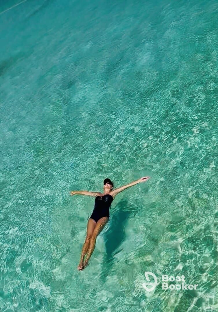 A woman floats serenely in crystal-clear waters, showcasing the perfect relaxation spot for a tropical getaway.