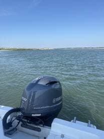 A close-up view of a Yamaha 200 outboard motor on a boat, set against a serene water backdrop, showcasing the vessel's engine and the tranquil environment.