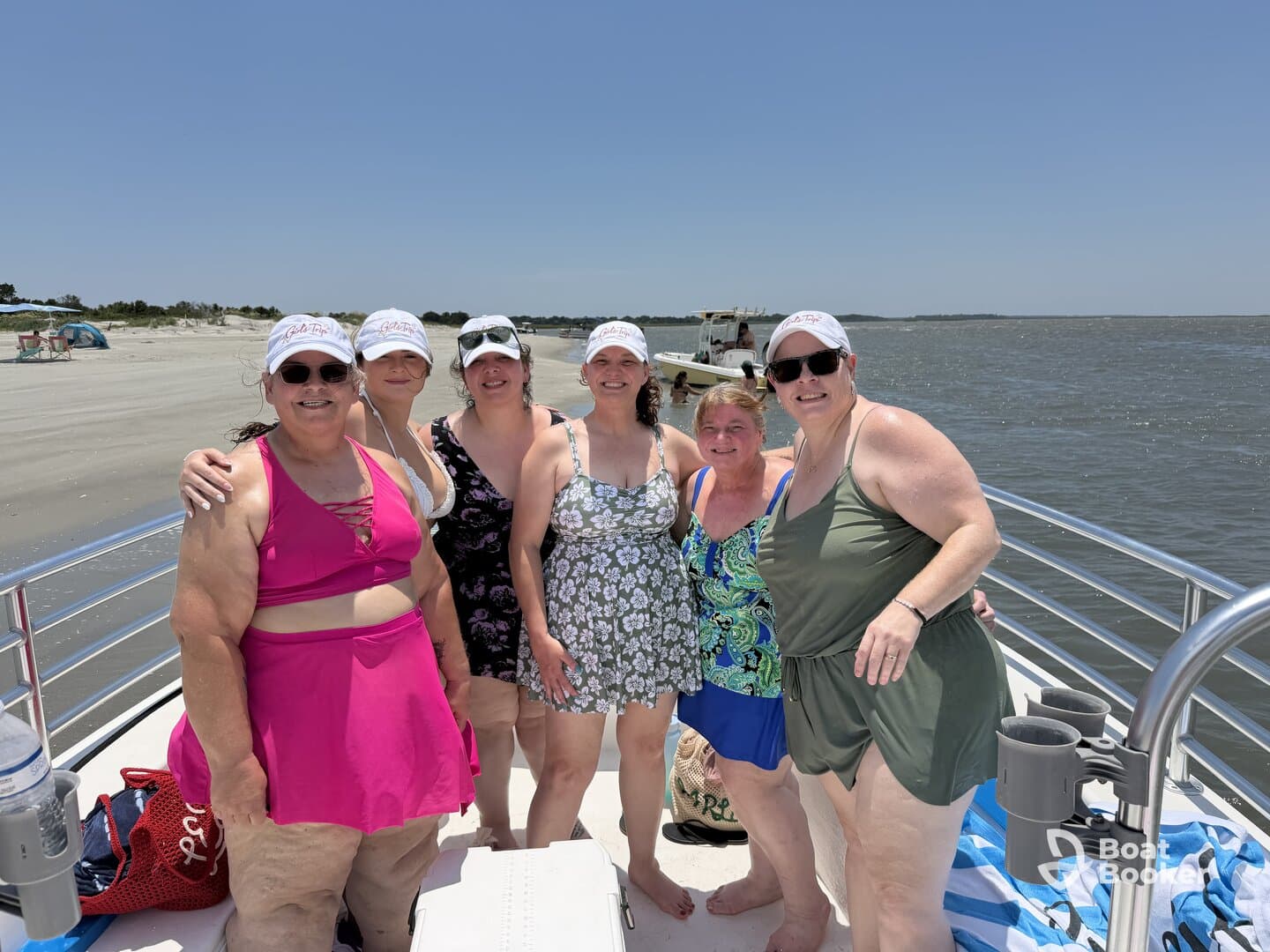 A cheerful group of friends poses on a pontoon boat, enjoying a sunny day at the beach — perfect for summer outings and celebrations on the water.