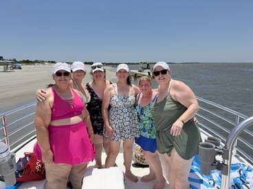 A cheerful group of friends poses on a pontoon boat, enjoying a sunny day at the beach — perfect for summer outings and celebrations on the water.