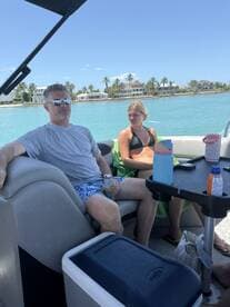 A group enjoys a relaxing day on the water, seated on a boat with drinks in hand, surrounded by beautiful waterfront homes.