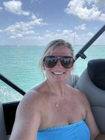 A joyful selfie of a woman enjoying a sunny day on a boat, with vibrant turquoise waters in the background — perfect for capturing memorable moments on the water.