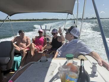 A lively group enjoys a day on the water, relaxing and sipping drinks aboard a boat — perfect for summer outings and celebrations.