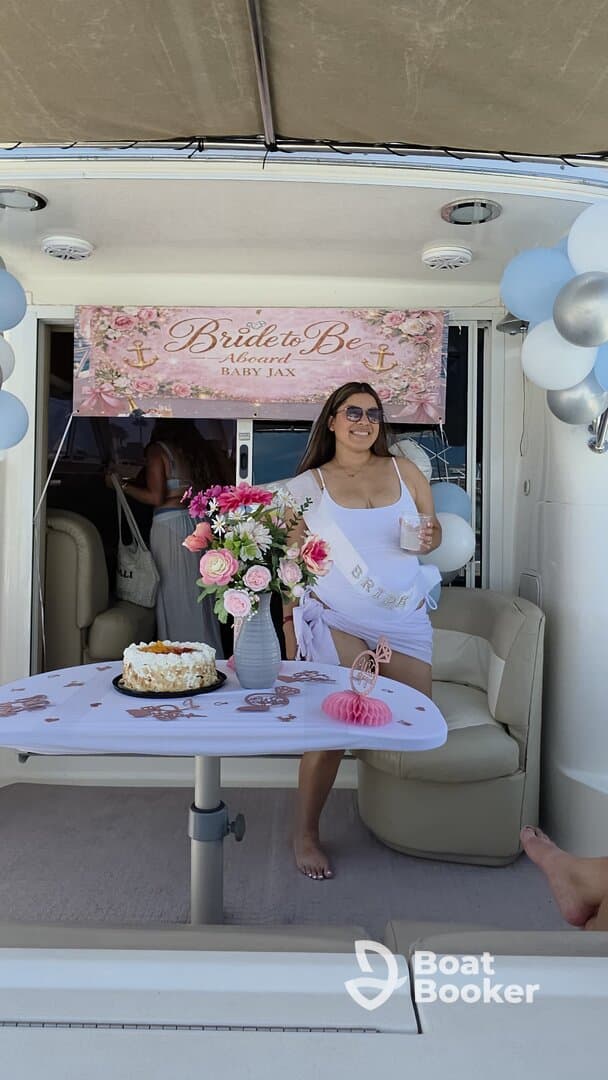 A joyful bride-to-be celebrates her upcoming wedding aboard a boat, surrounded by decorations and a cake, perfect for a memorable bachelorette party.