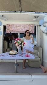 A joyful bride-to-be celebrates her upcoming wedding aboard a boat, surrounded by decorations and a cake, perfect for a memorable bachelorette party.