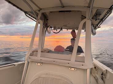 A serene view from the helm of a boat at sunset, showcasing the tranquil waters and a captain steering towards the horizon.